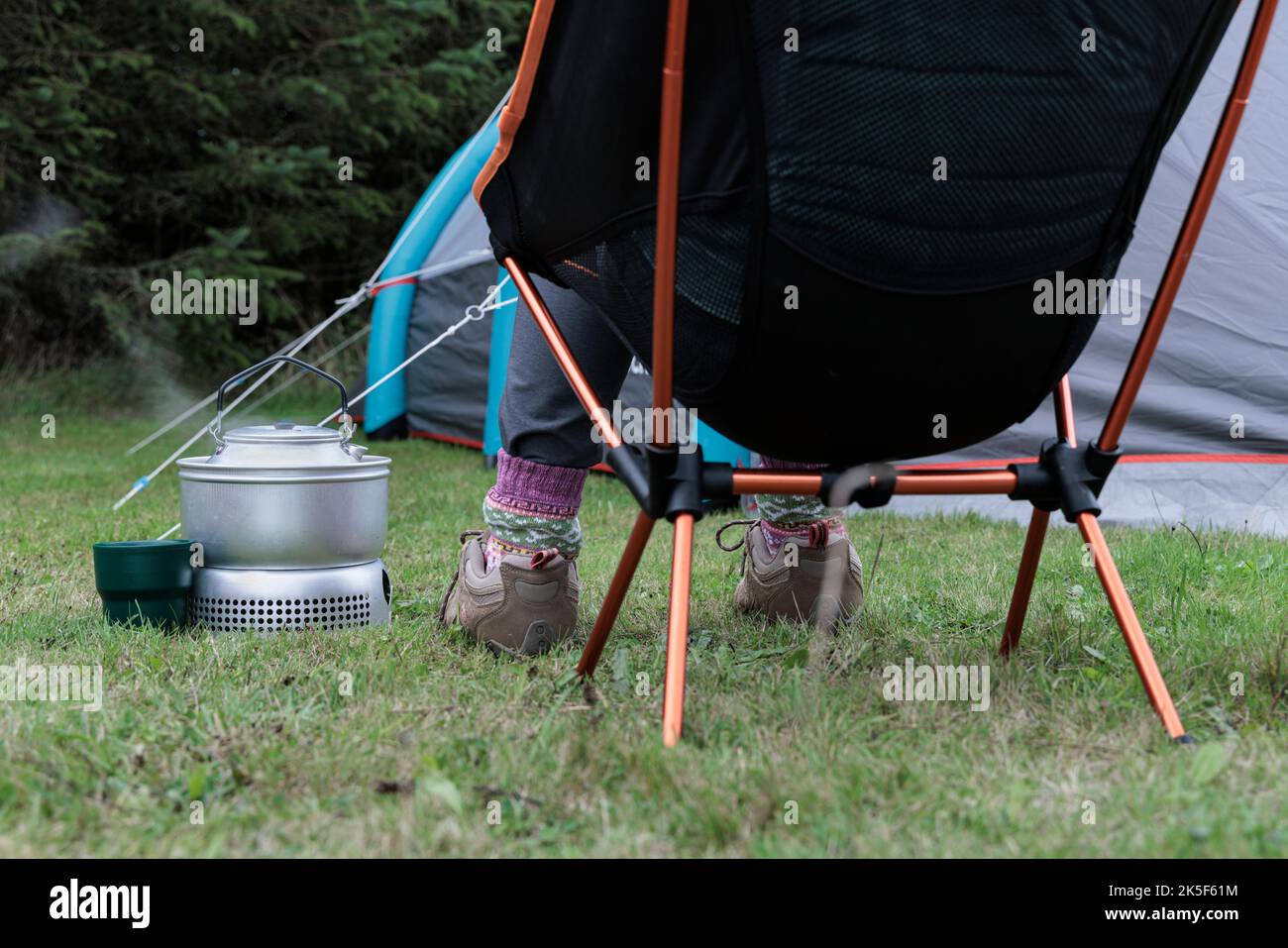 Mujer hirviendo un hervidor en una estufa de camping. Foto de stock