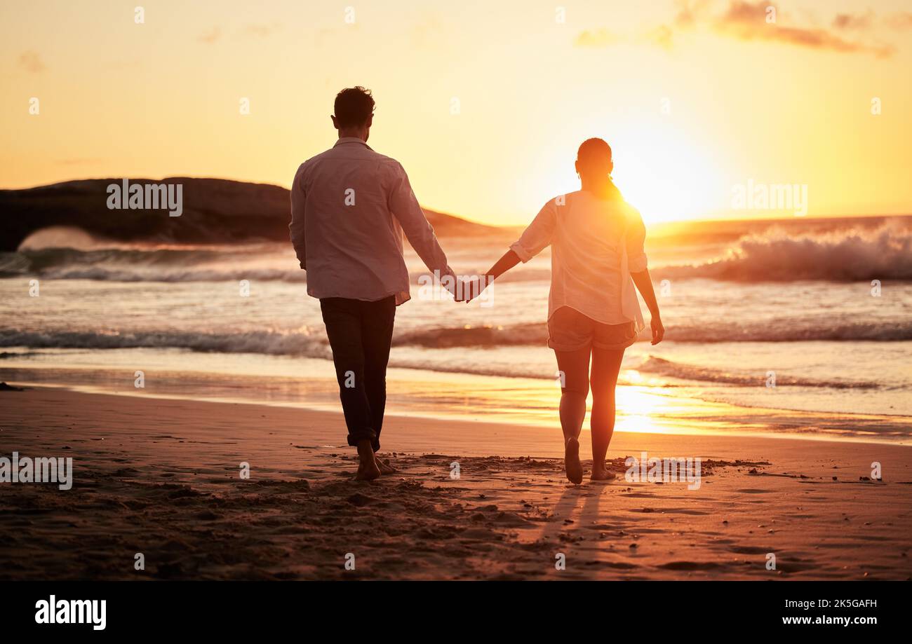 Puesta de sol, pareja agarrándose de la mano y caminando por la playa con un hermoso crepúsculo. El amor, el romance y el hombre feliz y la mujer que pasan tiempo junto Puesta de sol, pareja agarrándose de la mano y caminando por la playa con un hermoso crepúsculo. El amor, el romance y el hombre feliz y la mujer que pasan tiempo junto