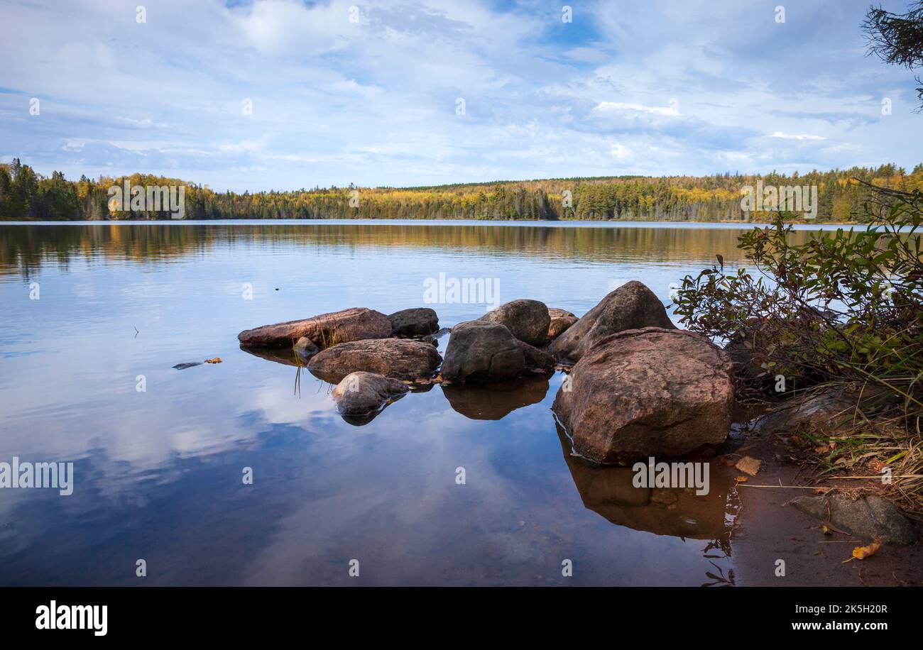 Vista de bajo ángulo de un lago tranquilo con rocas en el norte de Minnesota en un hermoso día de otoño Foto de stock