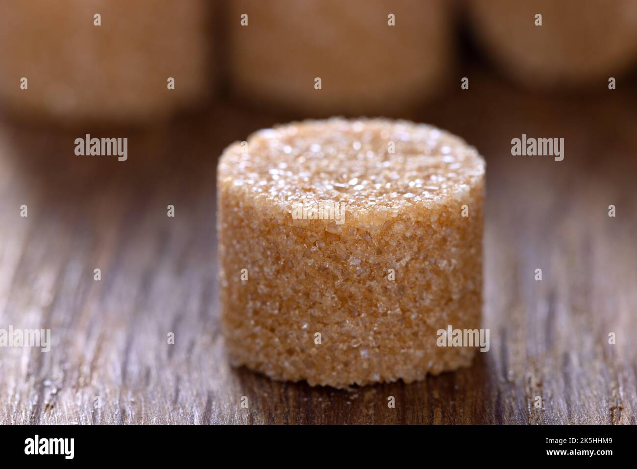 Una forma de azúcar redondo marrón sobre una vieja tabla de madera oscura - vista de cerca Foto de stock