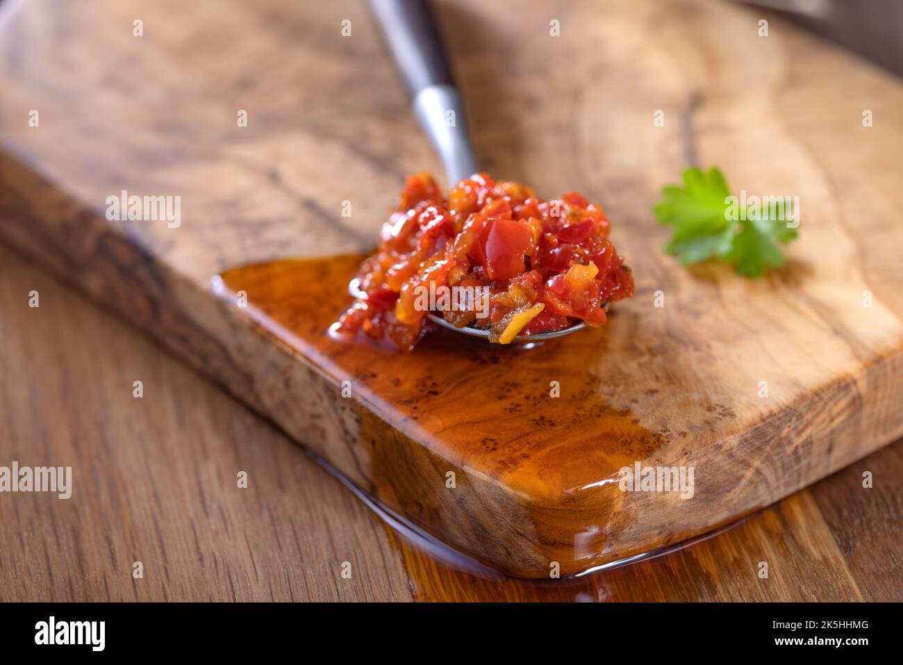 Pasta caliente hecha de chiles y pimientos con aceite en una cucharadita - primer plano Foto de stock