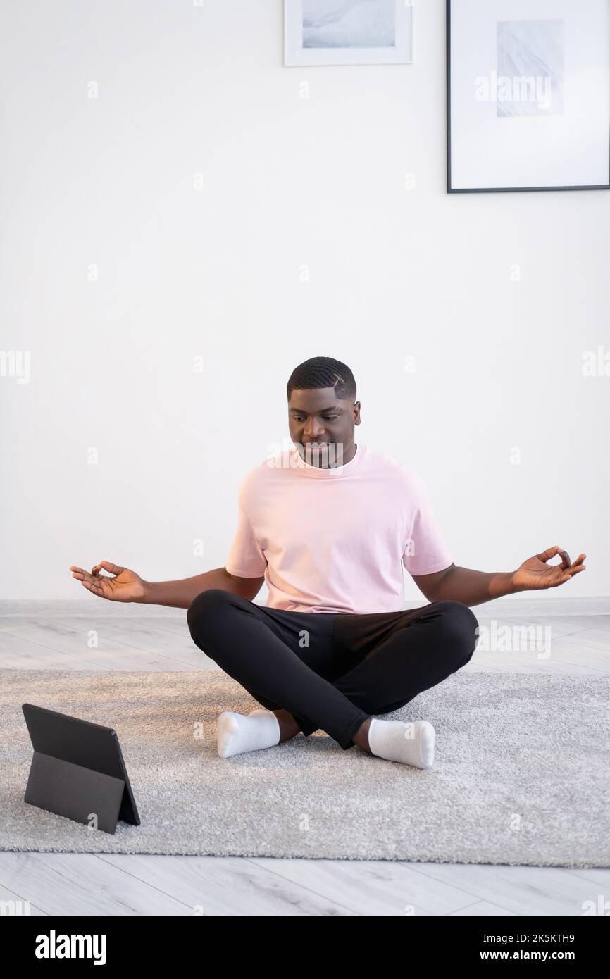 práctica de yoga curioso negro hombre lección en línea nuevo Foto de stock