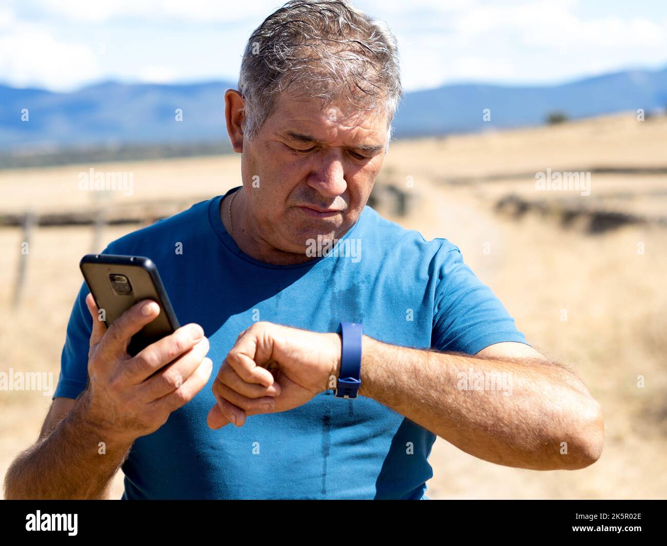 Anciano español mirando un reloj deportivo haciendo deportes. Aplicación RUNNER SPORT Foto de stock