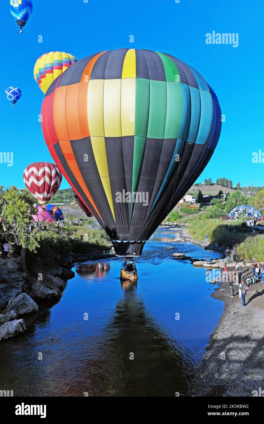 Los coloridos globos de aire caliente surcan el cielo sobre el río San Juan en Pagosa Springs, Colorado durante el Colorfest Balloon Rally 2022. Foto de stock