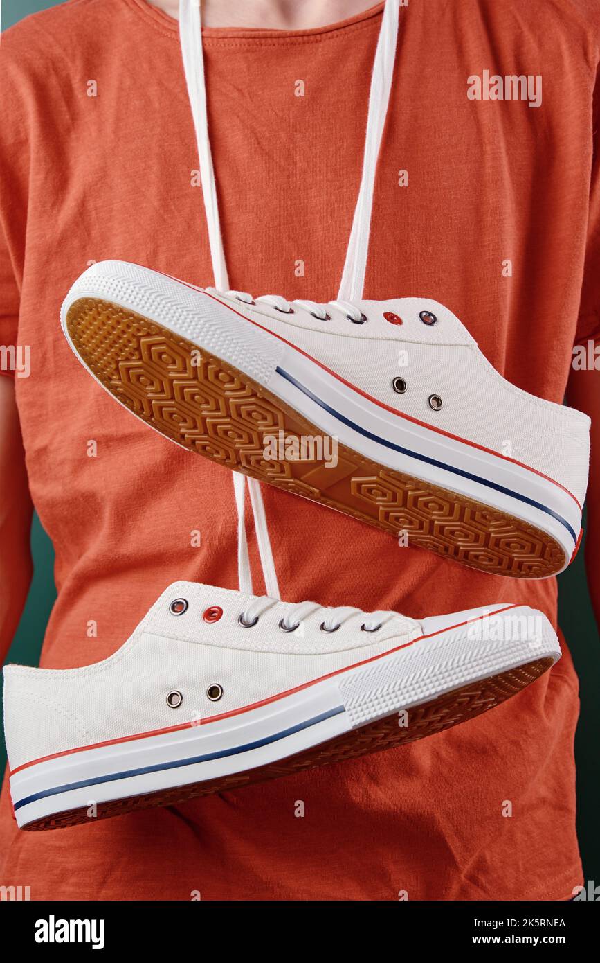 Zapatillas deportivas blancas colgando en el cuello de adolescente con  encaje de zapatos, calzado informal de moda para primeros planos Fotografía  de stock - Alamy