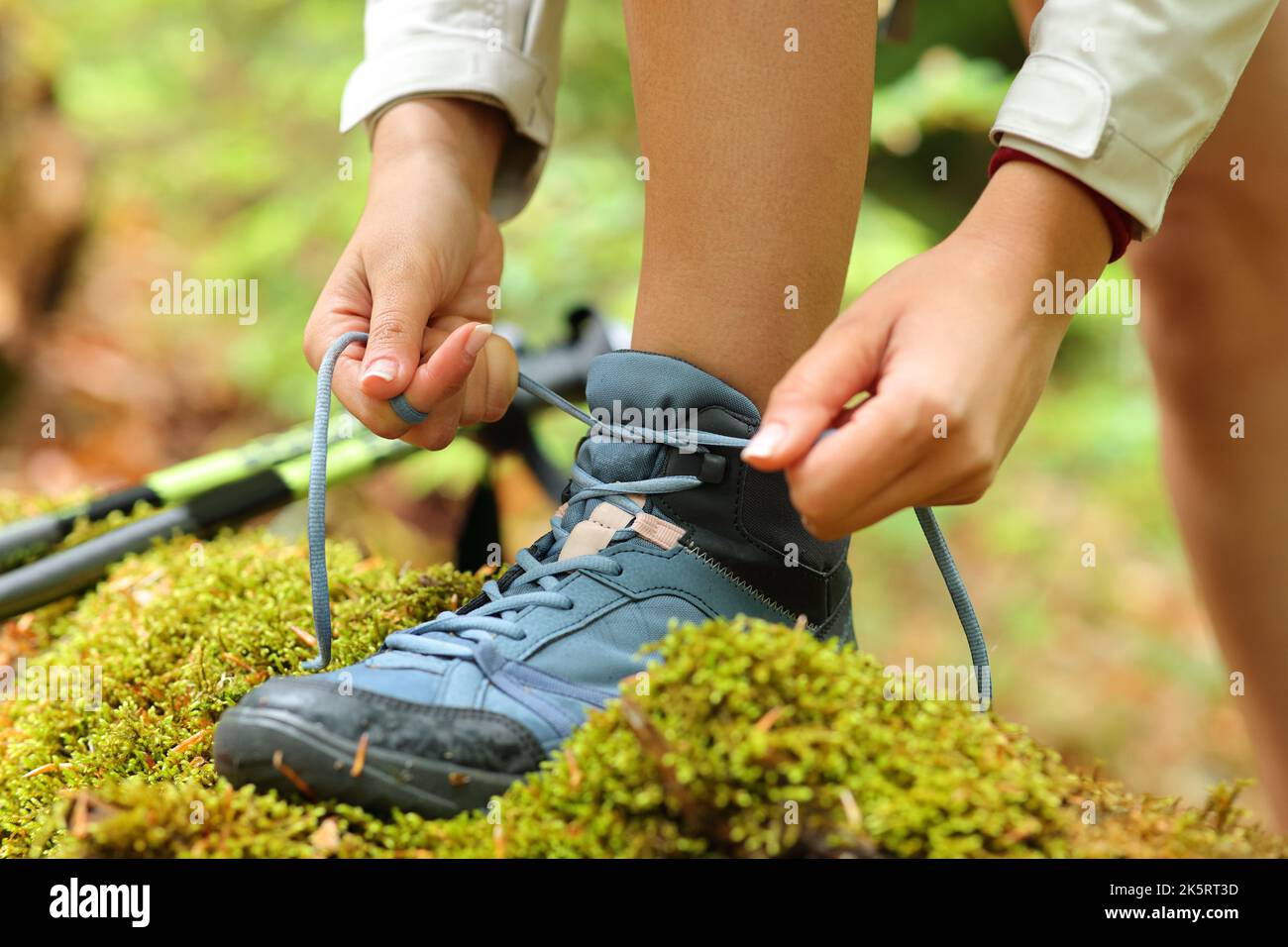 Primer plano de las manos de un excursionista atando cordones de botas de trekking en la montaña Foto de stock