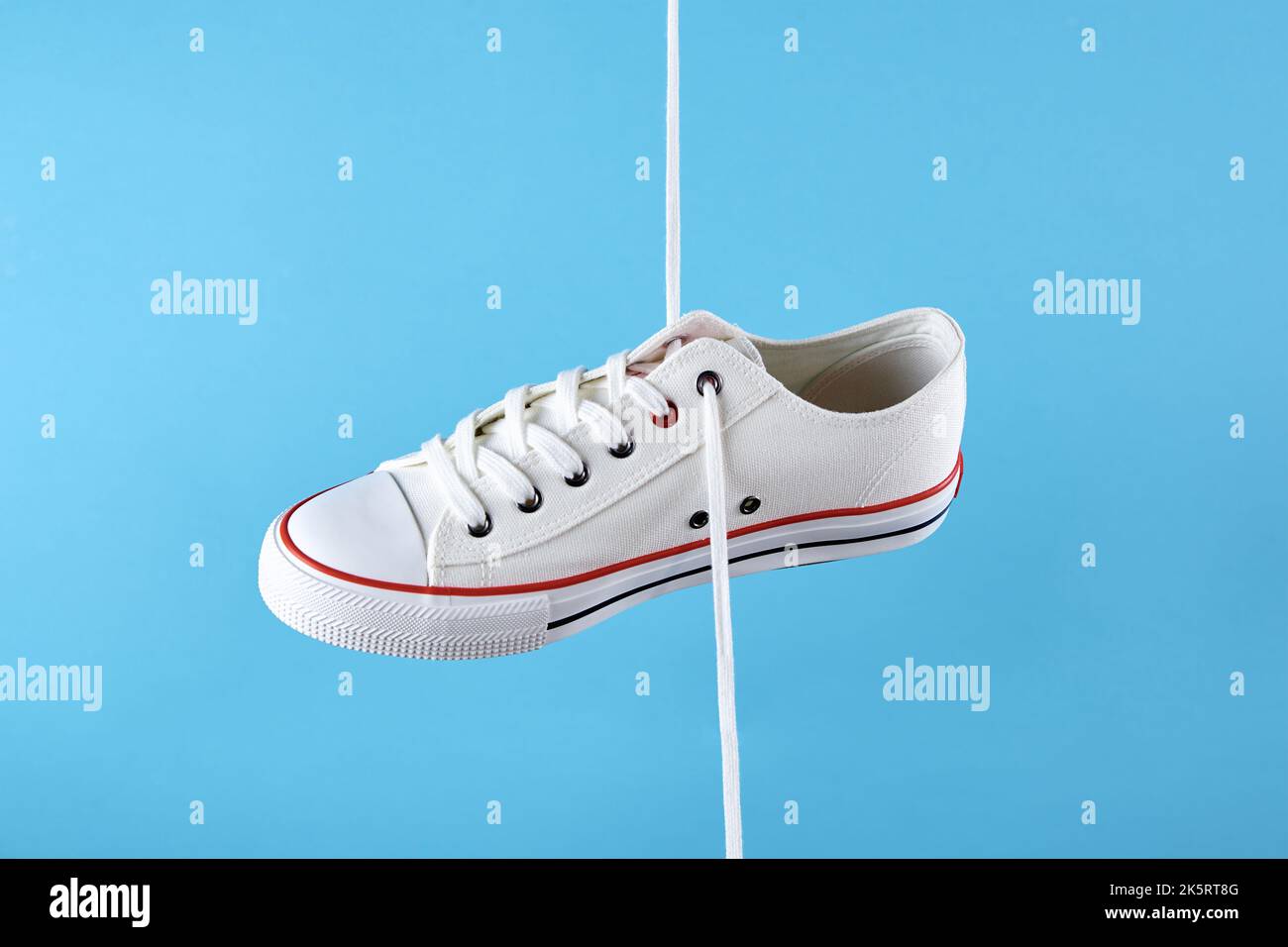 Zapatillas deportivas blancas para mujer con cordones para zapatillas sobre  fondo azul, zapatos informales de moda de primer plano, diseño minimalista  creativo con espacio de copia Fotografía de stock - Alamy