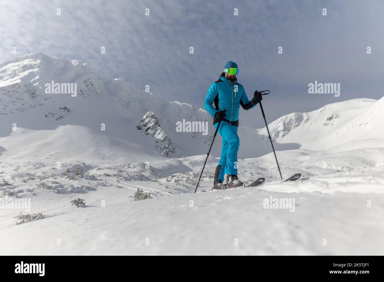 Hombre esquiador de campo a pie hasta la cumbre de un pico nevado en el Bajo Tatras en Eslovaquia. Foto de stock