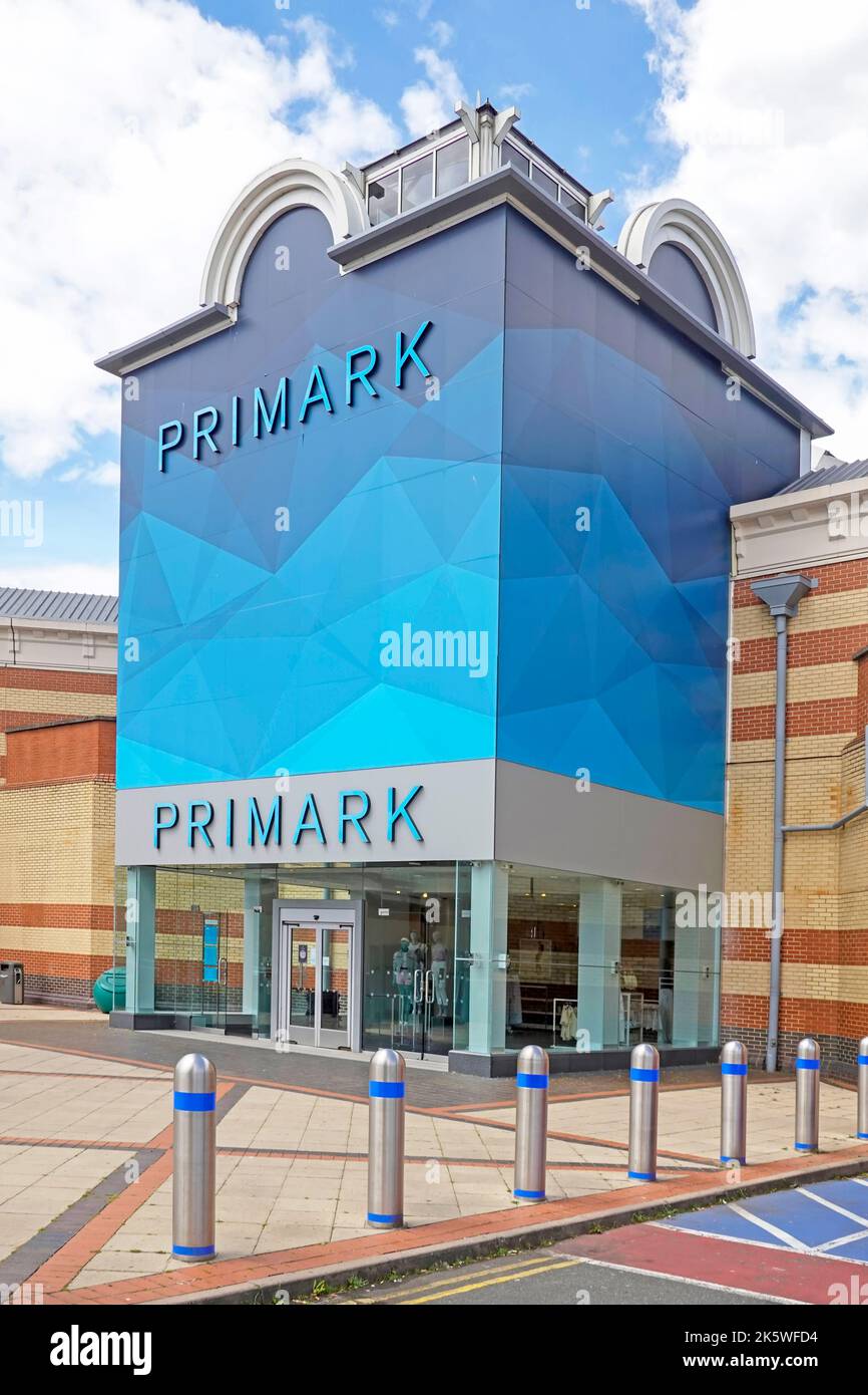 Fachada azul por encima de la entrada de la tienda Primark al por menor de ropa de negocios y bollards de seguridad Lakeside shopping center Malls West Thurrock Essex England UK Foto de stock