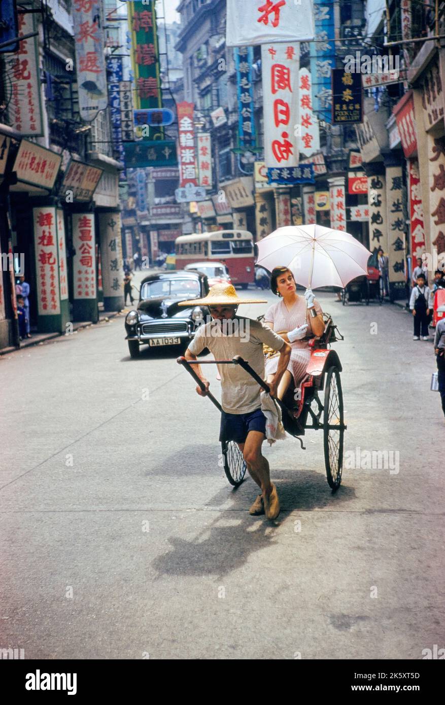 Hombre tirando de la mujer en Rickshaw, Hong Kong británico, Toni Frissell Collection, 1959 Foto de stock