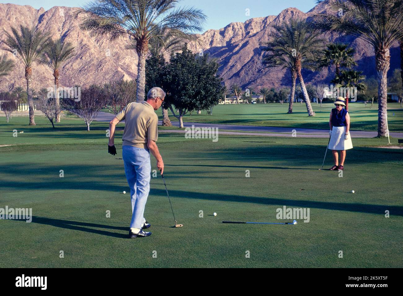 Hombre y mujer en Putting Green, Palm Desert, California, EE.UU., Toni Frissell Collection, Marzo 1969 Foto de stock