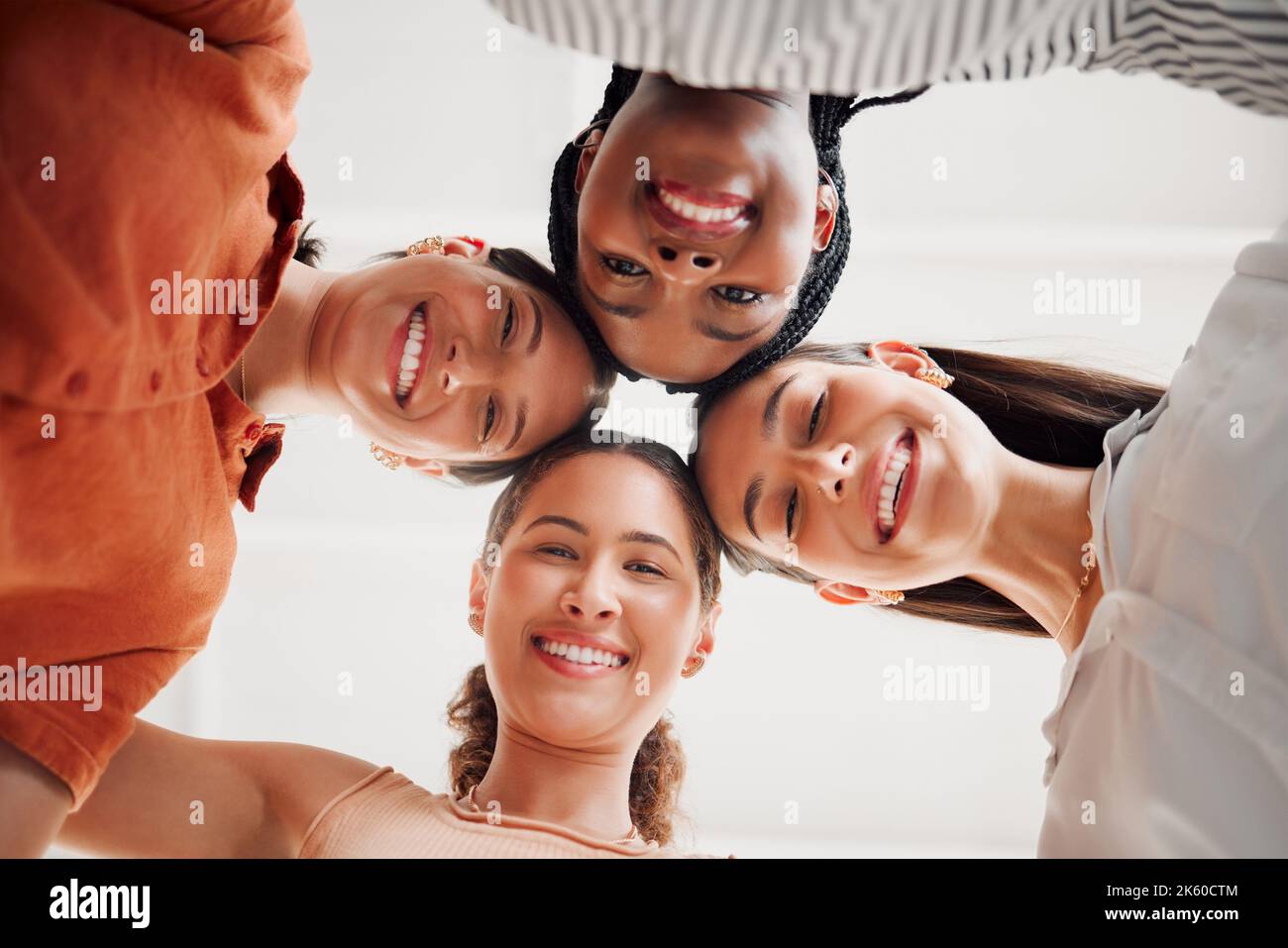 Retrato de mujeres de negocios felices que unen sus cabezas en un círculo en una oficina en el trabajo. Grupo diverso de empresarios alegres divirtiéndose Foto de stock