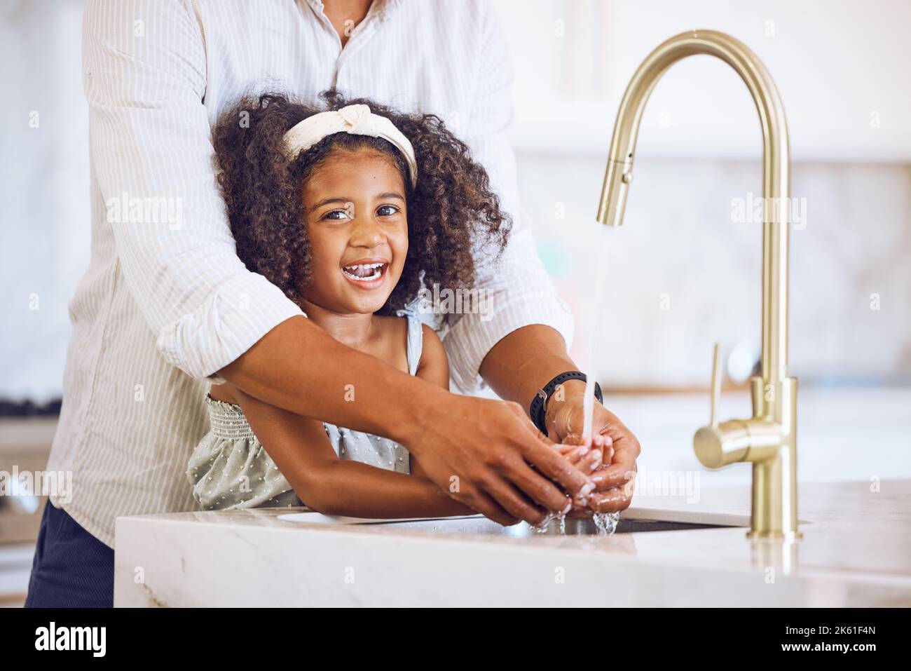 Retrato de una familia lavándose las manos para la higiene, para detener  los gérmenes y la salud en la cocina en casa. Feliz, sonría y padre  ayudando a su hijo a limpiar