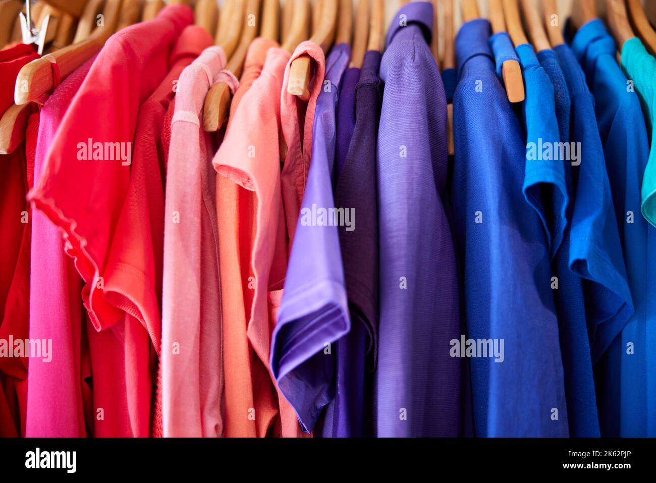 Ropa sostenible de colores Colgante en carril en la tienda de beneficencia o Thrift Venta de moda sostenible Foto de stock