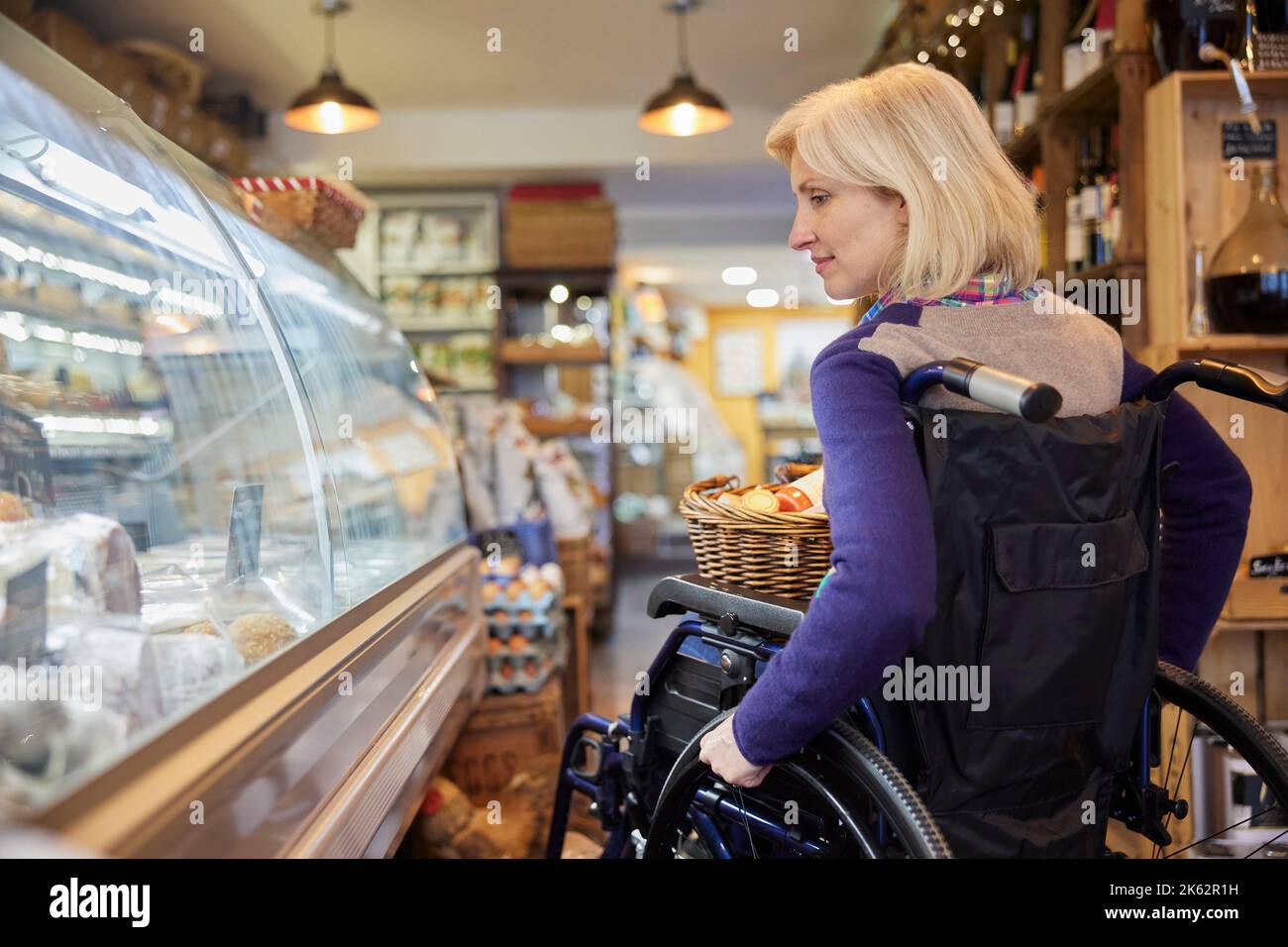 Mujer en silla de ruedas Compras para comida en Delicatessen Foto de stock