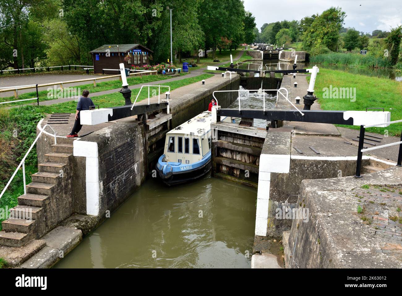 Barco estrecho del canal que pasa a través de las puertas de bloqueo en el trayecto de 21 esclusas en Hatton Locks en el Canal Grand Union, Warwick, Warwickshire Foto de stock