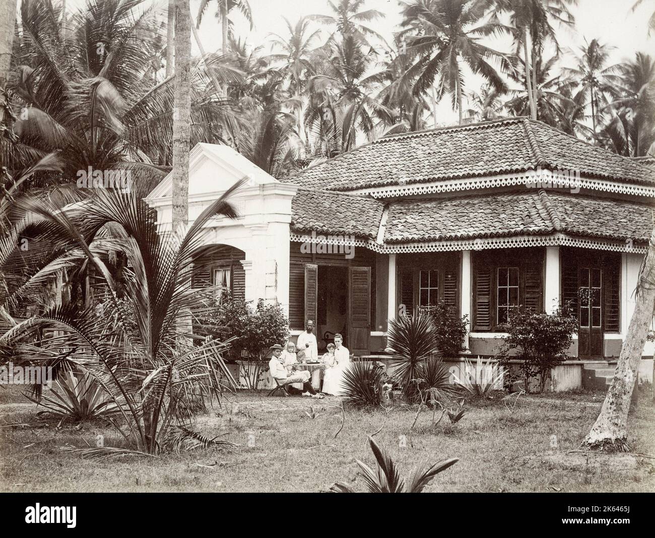 Fotografía del siglo XIX vintage - familia europea fuera de su bungalow colonial, con un sirviente, Singapur o el sudeste asiático ubicación. Foto de stock