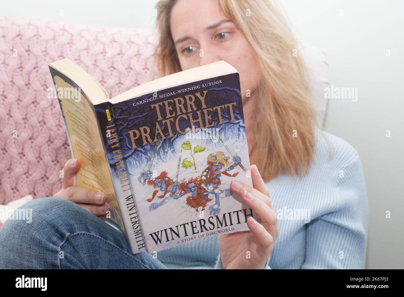 Una mujer leyendo el libro Wintersmith de Terry Pratchett Foto de stock