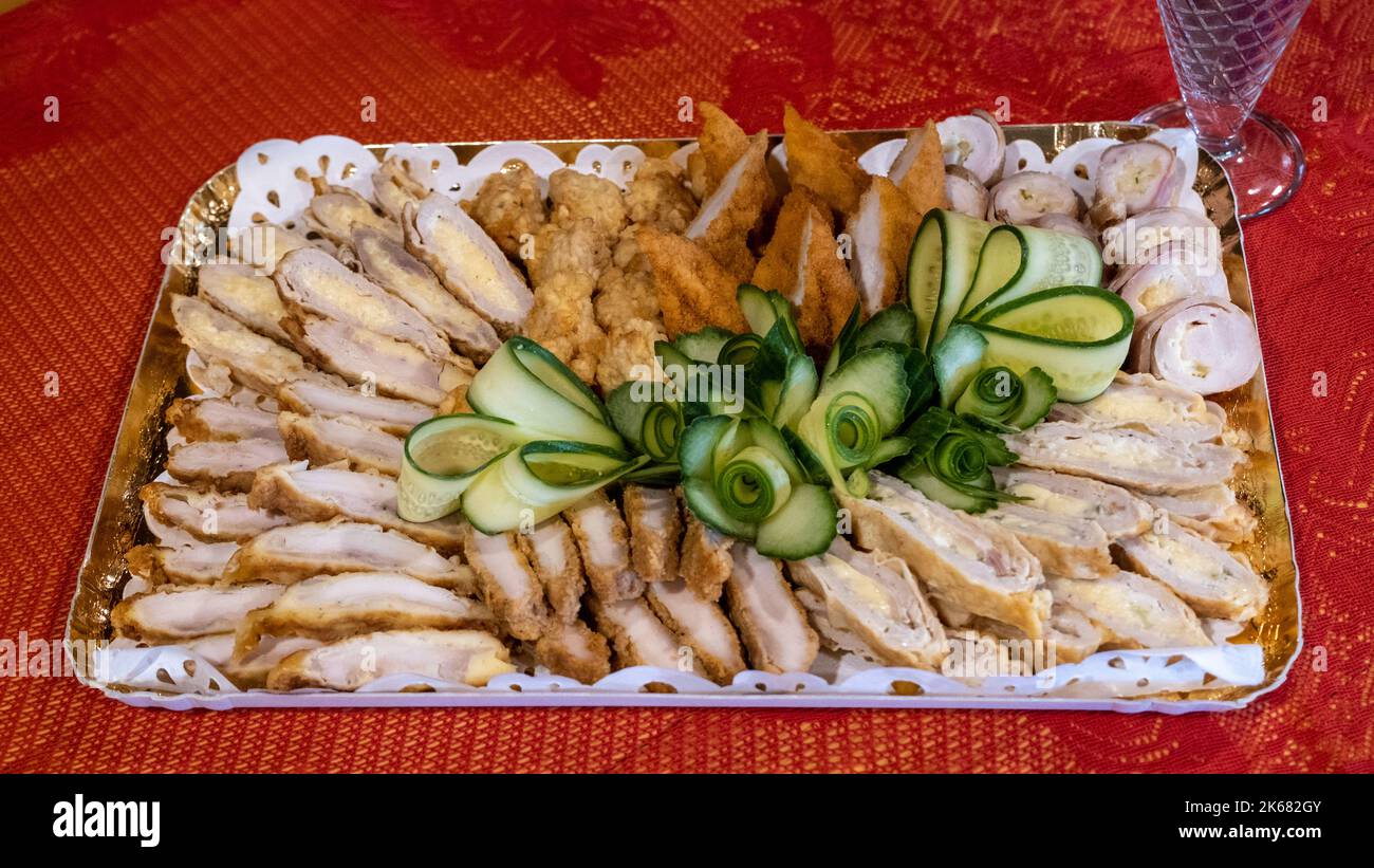 Un plato de deliciosa carne de pollo condimentada decorada con rodajas de pepino fresco Foto de stock