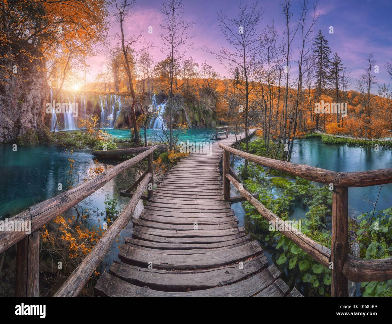Cascada y camino de madera en el bosque de naranja en los lagos de Plitvice Foto de stock