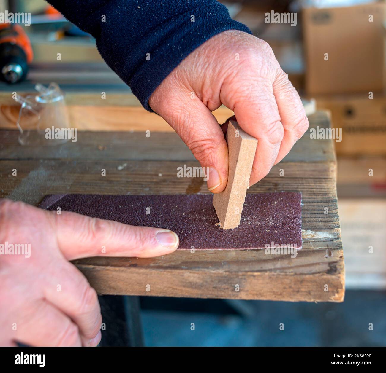lijado de tablas de madera con papel de lija en el taller Foto de stock