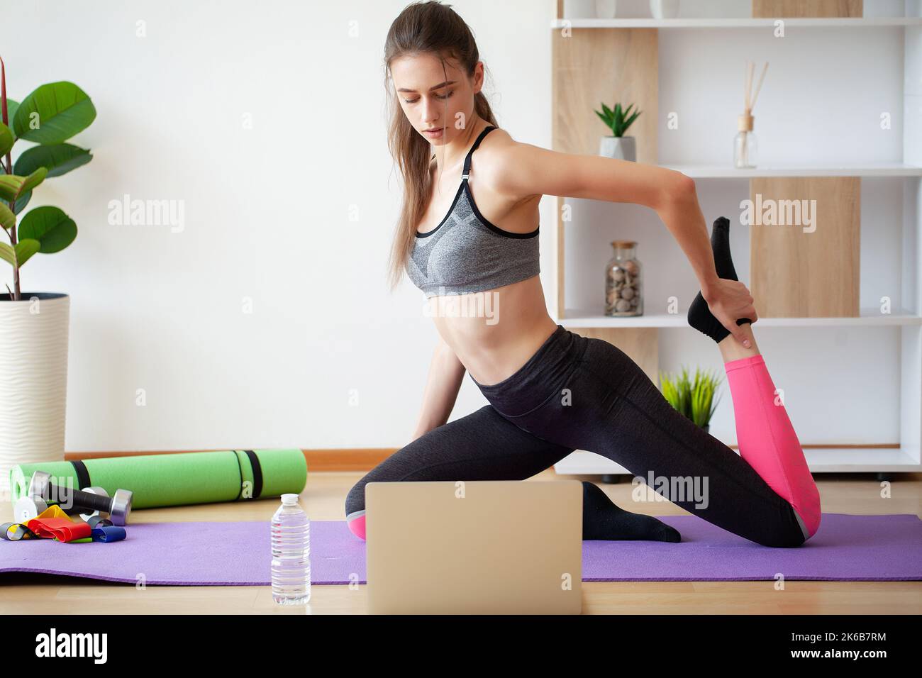 Mujer activa y alegre haciendo ejercicio en casa con el ordenador portátil  Fotografía de stock - Alamy