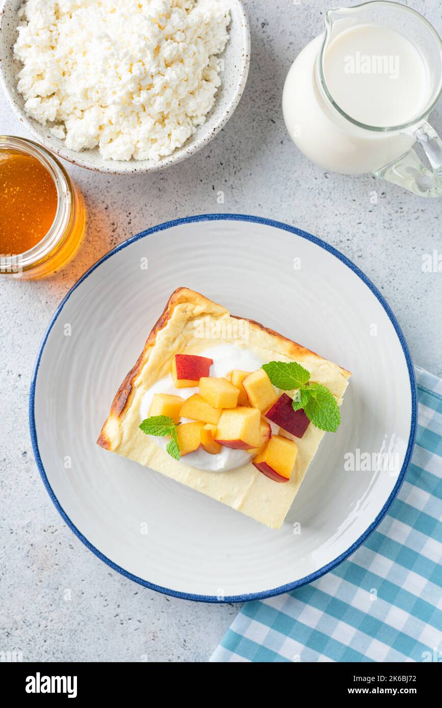 Cazuela de queso cottage servida con frutas y crema agria. Pudding de queso dulce para el desayuno Foto de stock