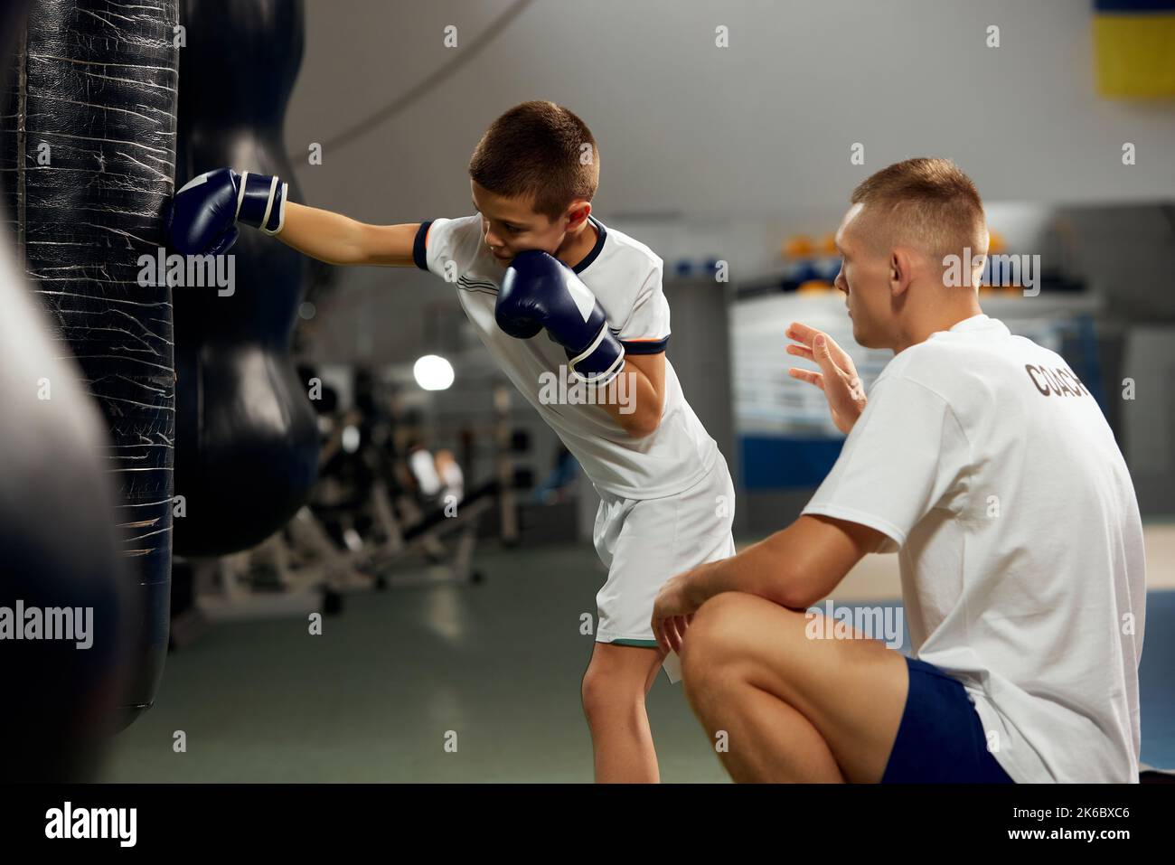 Dos atletas, el hijo y el padre están haciendo deportes en el gimnasio. Entrenamiento de boxer principiante con su entrenador ar boxing ring, en interiores. Deporte, potencia, energía y actividad Foto de stock