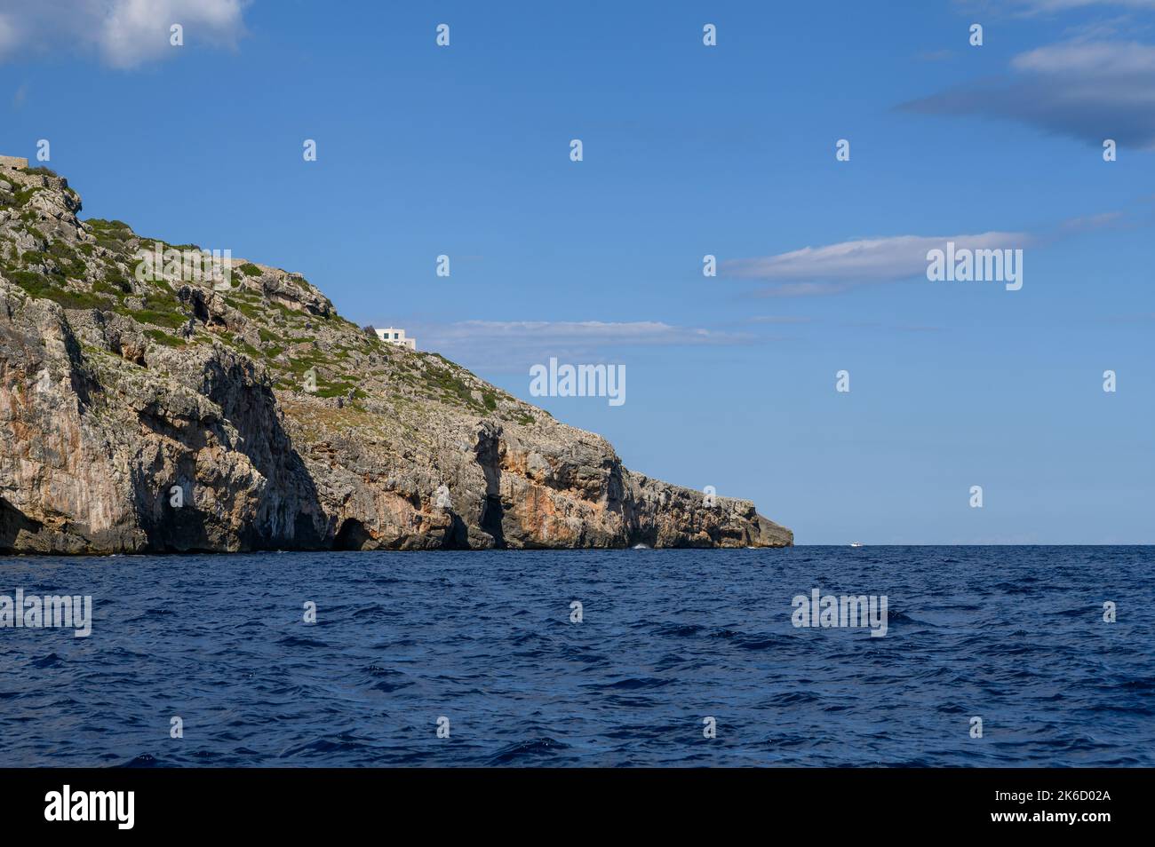 Una pequeña casa blanca encaramada en la ladera de un acantilado en la