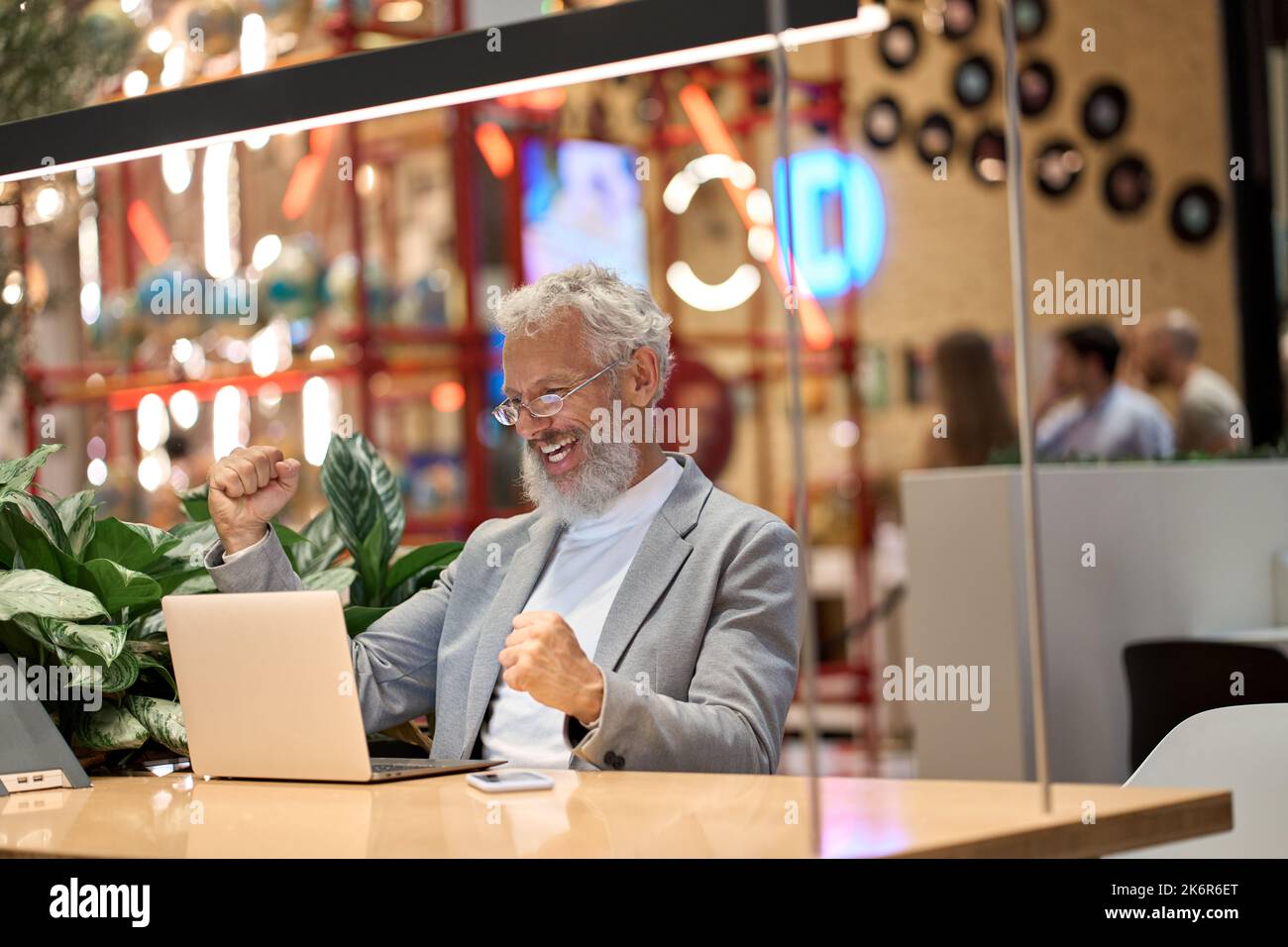 Feliz viejo hombre de negocios senior inversor mirando el portátil celebrando los beneficios. Foto de stock