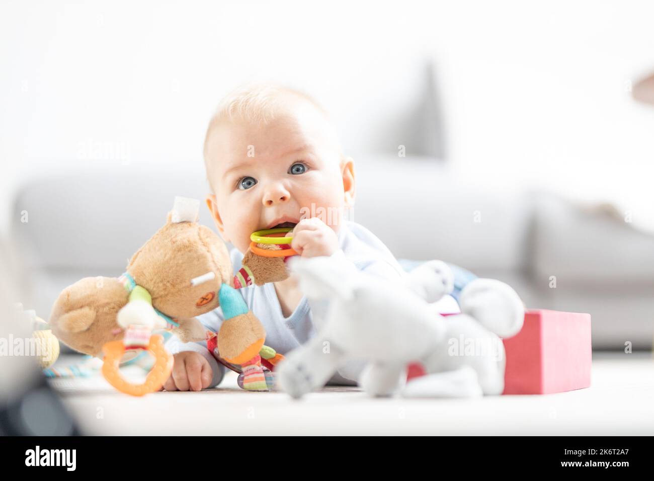 Niño lindo jugando con juguetes en la colchoneta en casa Centro de actividades y juegos para el desarrollo infantil temprano. Bebé jugando en casa. Foto de stock