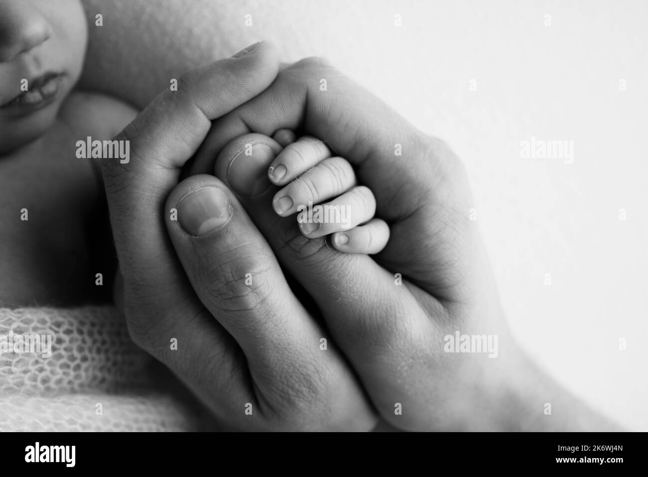 Un recién nacido se aferó al dedo de la madre, del papá. Las manos de los padres y del bebé se acercan. Un niño confía y la mantiene apretada. Foto de stock
