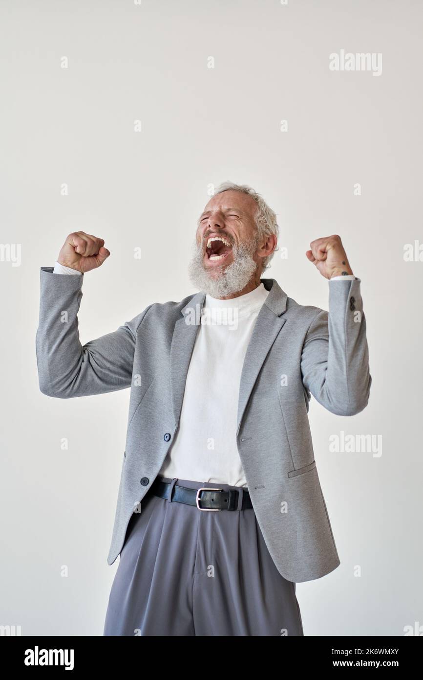 Entusiasmado empresario de edad avanzada inversor levantando puños celebrando aislados sobre blanco. Foto de stock