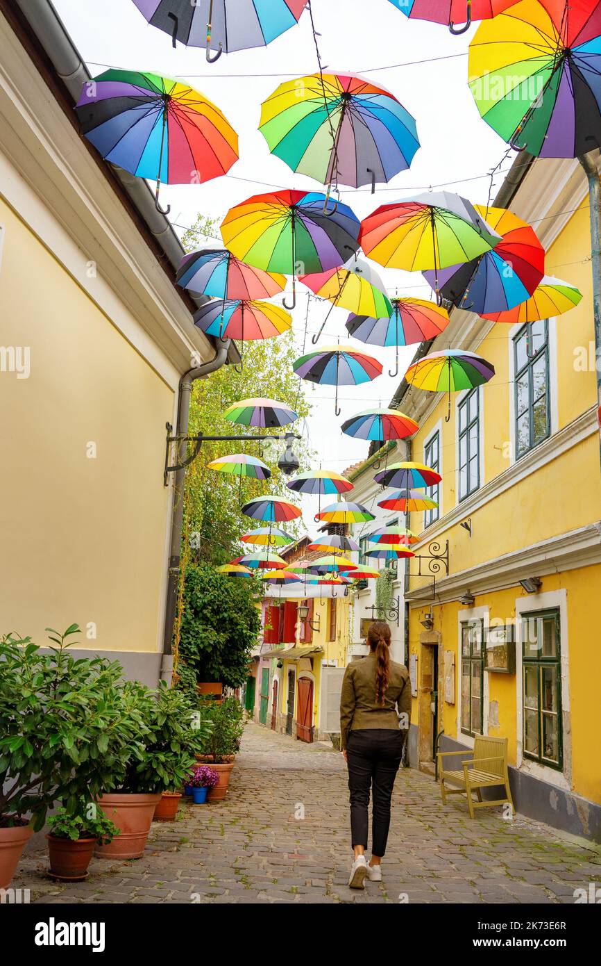turismo mujer caminando por las calles de Szentendre bajo coloridas sombrillas Foto de stock