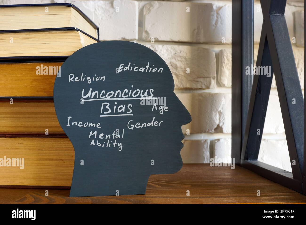 Una pila de libros y una cabeza con una inscripción de sesgo inconsciente. Foto de stock