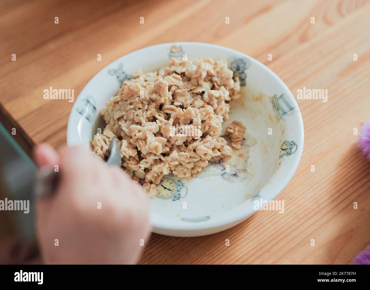 una chica toma un desayuno de avena en la mesa de la cocina Foto de stock