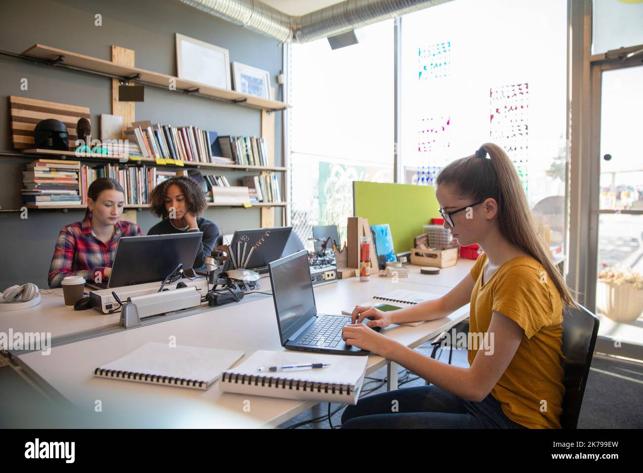 Tres estudiantes que usan computadoras portátiles en el taller de tecnología Foto de stock