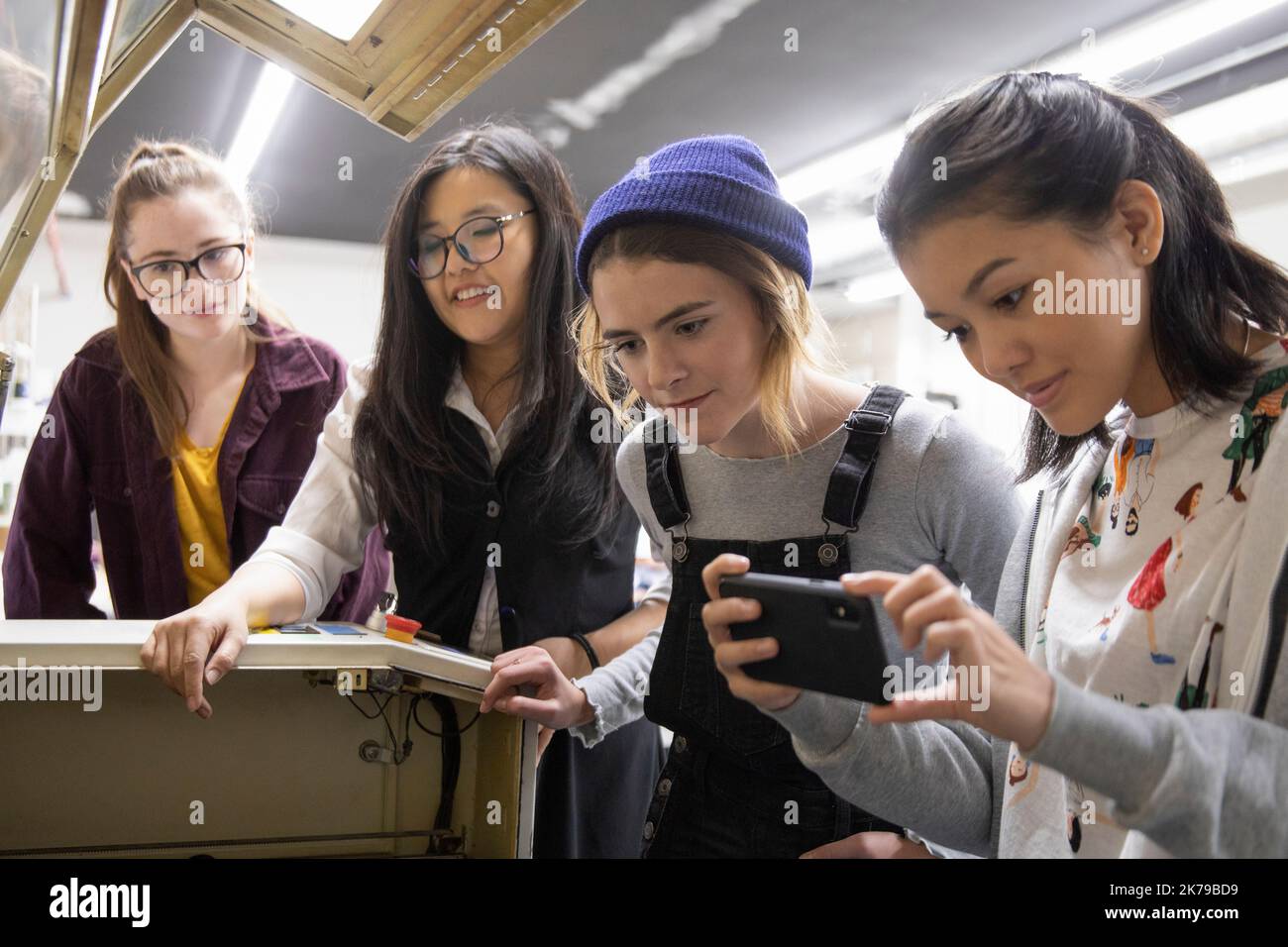 Estudiantes que usan un smartphone para tomar fotografías en un estudio técnico Foto de stock