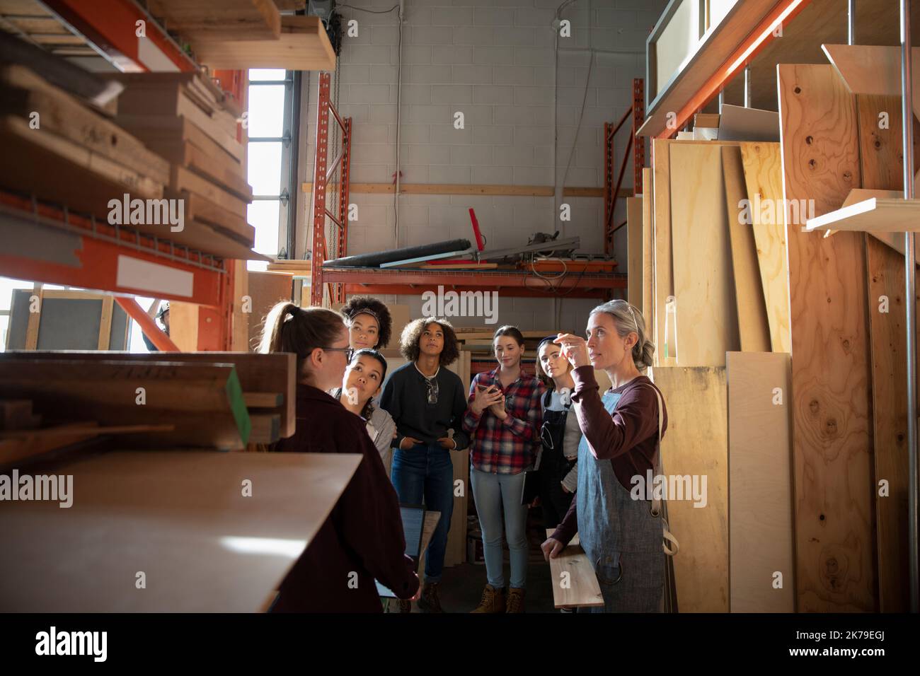 Mujer madura hablando con los estudiantes en almacenamiento de madera Foto de stock