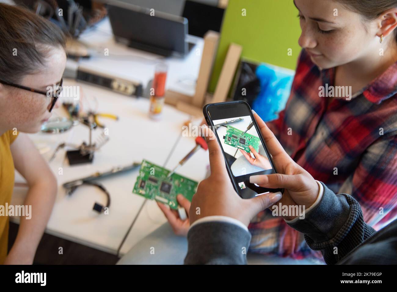 El estudiante está fotografiando una placa de circuito con un smartphone en clase de tecnología Foto de stock