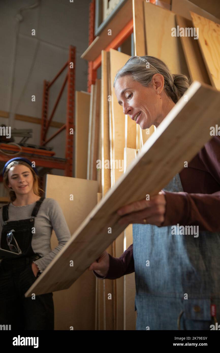 Mujer madura seleccionando madera en taller de carpintería Foto de stock