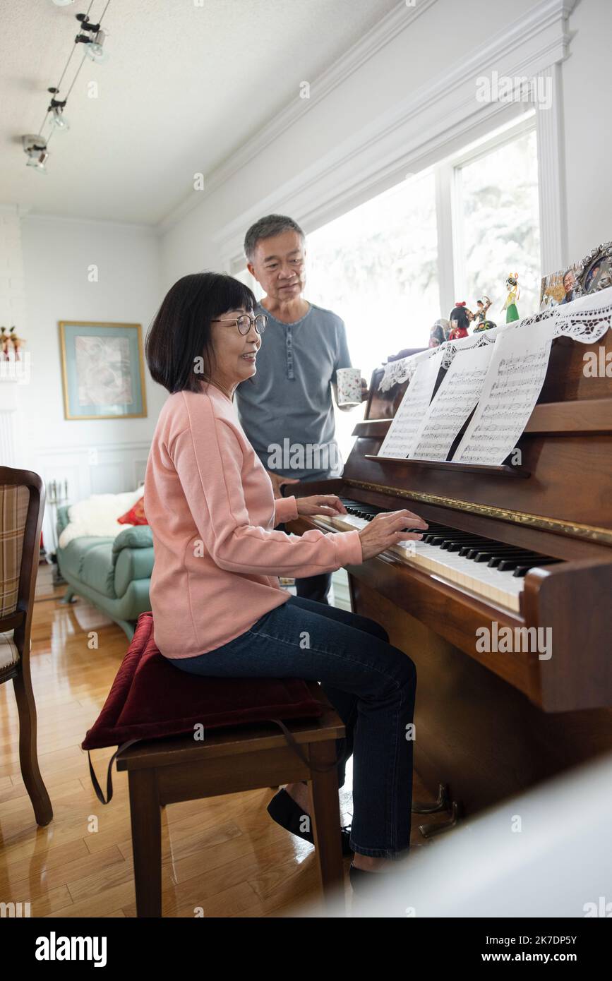 El hombre mayor que mira a su esposa toca el piano en casa Fotografía de  stock - Alamy