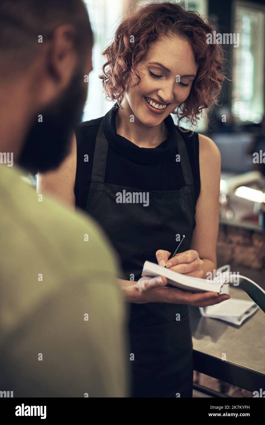 Mis clientes nunca se van sin recibo. un peluquero joven de pie y escribiendo un recibo para su cliente después de labrar su pelo en su salón. Foto de stock