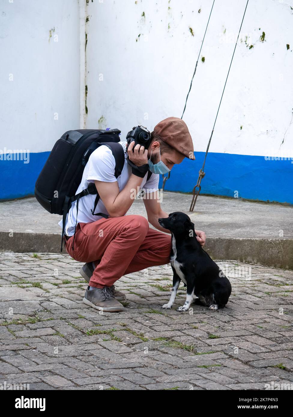 Un hombre blanco se alimenta de un perro blanco y negro en la calle Foto de stock