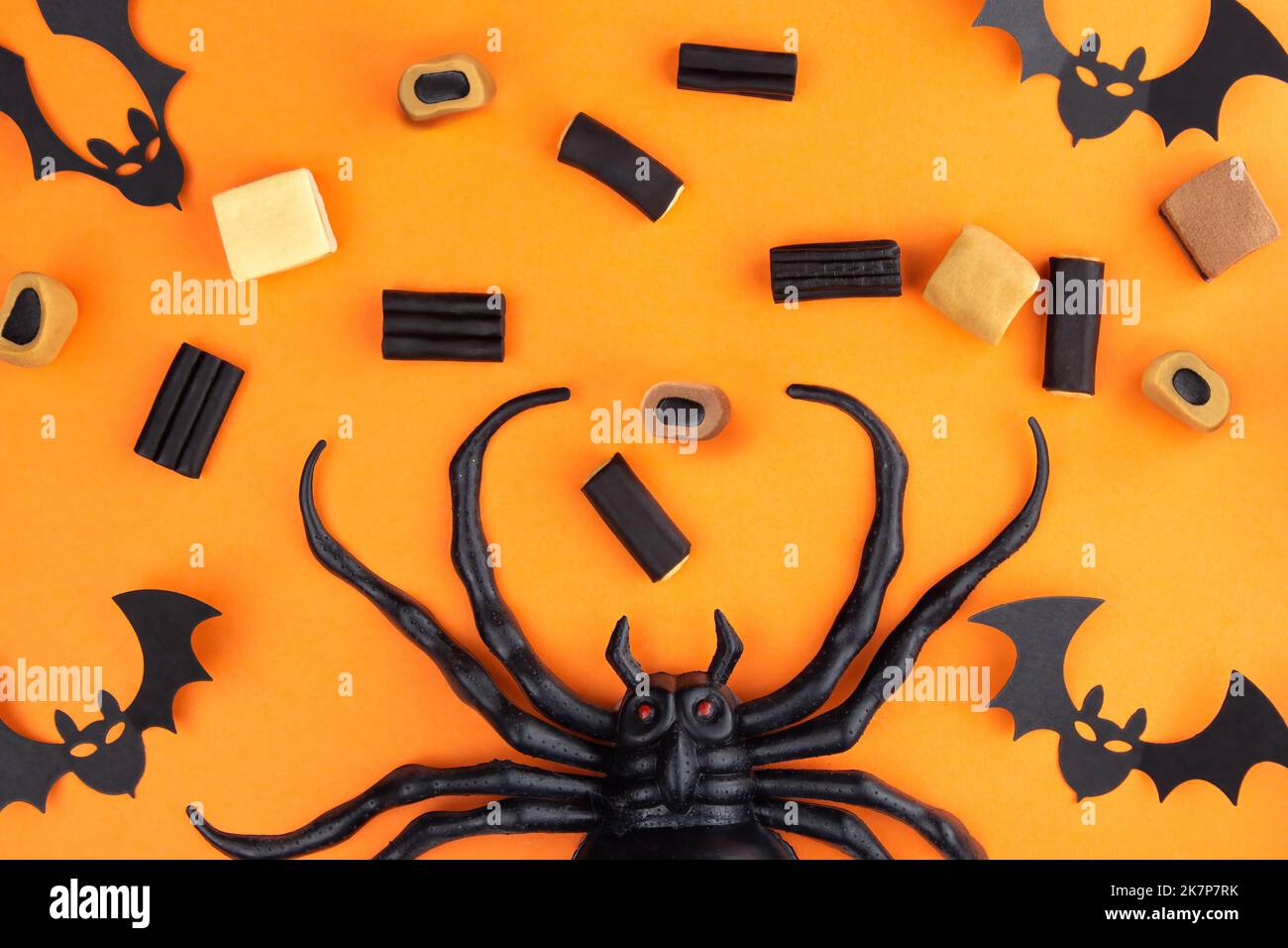 Sobre un fondo anaranjado abajo en el centro de la araña, hay laca, caramelo y caramelos de mascar, en las esquinas de murciélagos tallados en pa negra Foto de stock