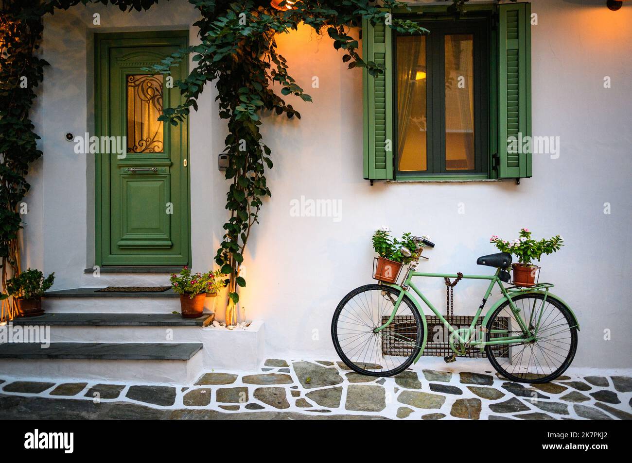 Flor plantada en una vieja bicicleta contra una pared en la ciudad de Skiathos Grecia. Foto de stock
