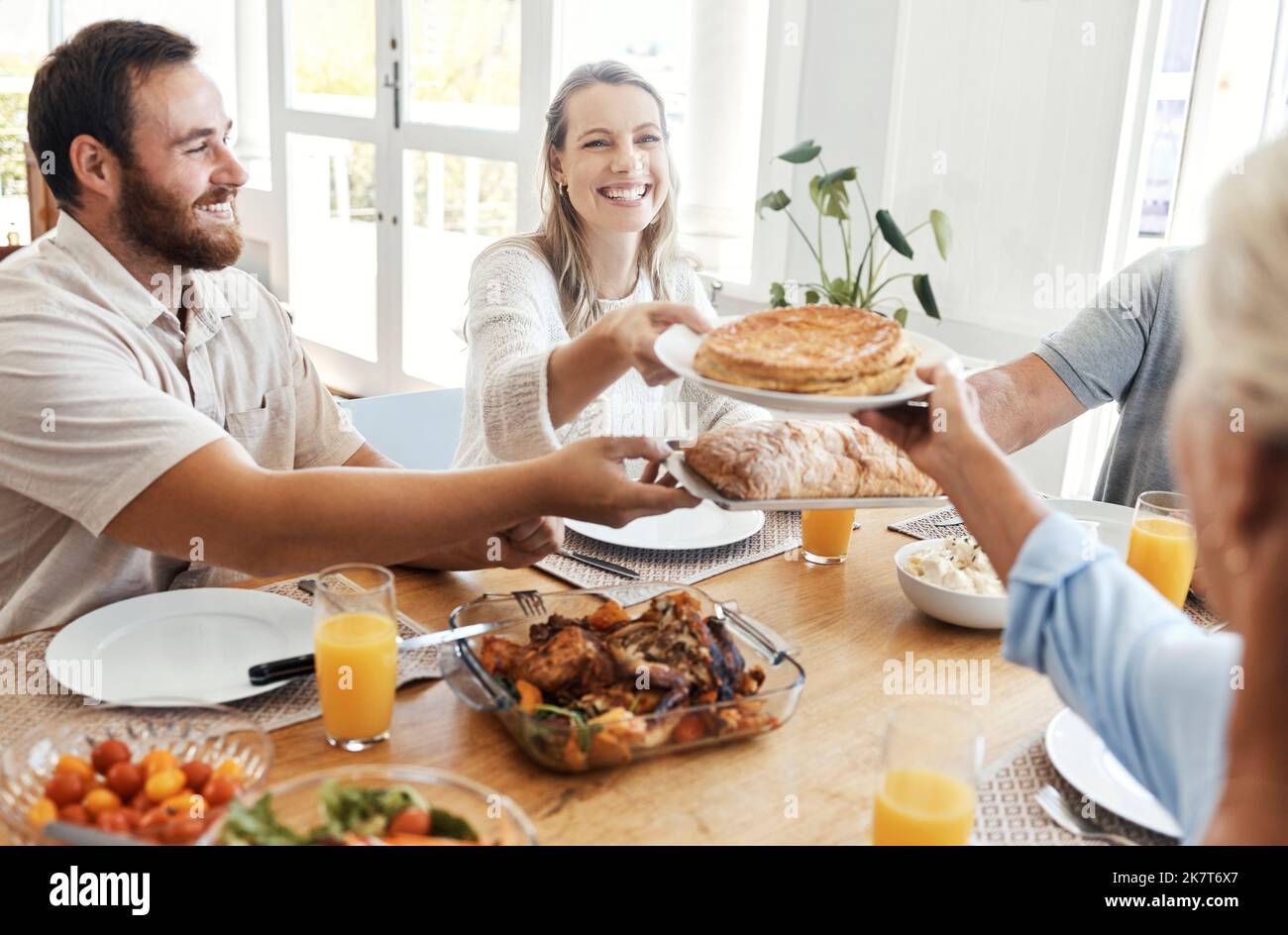 Gran familia, almuerzo y comida en casa comedor con la gente compartiendo una comida. Amor, feliz y familiares comiendo comida, pan y delicioso pollo gourmet Foto de stock