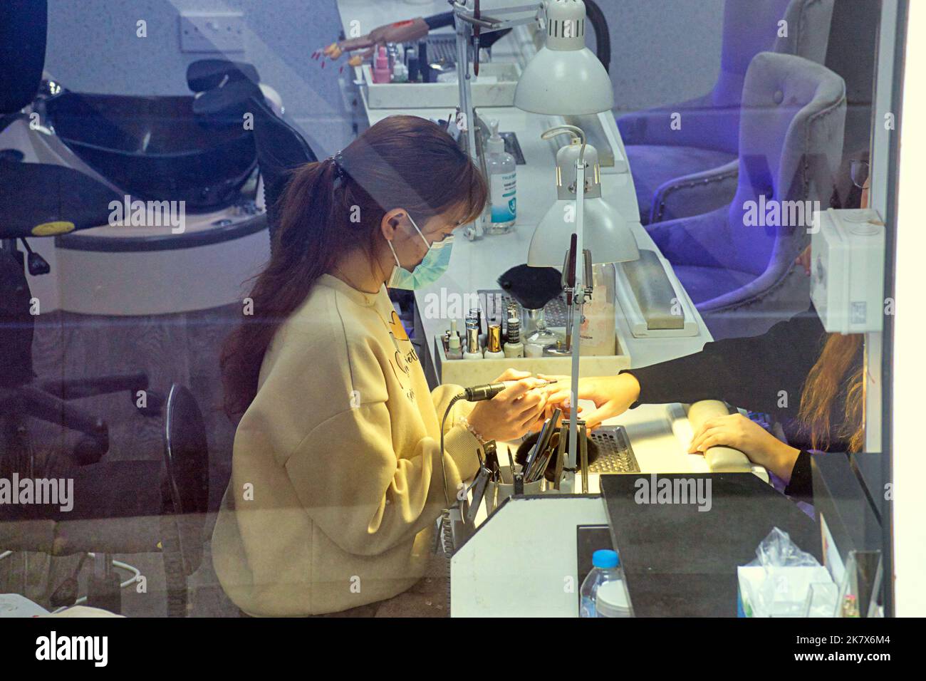 Chica china haciendo uñas de los clientes en salón de uñas Foto de stock