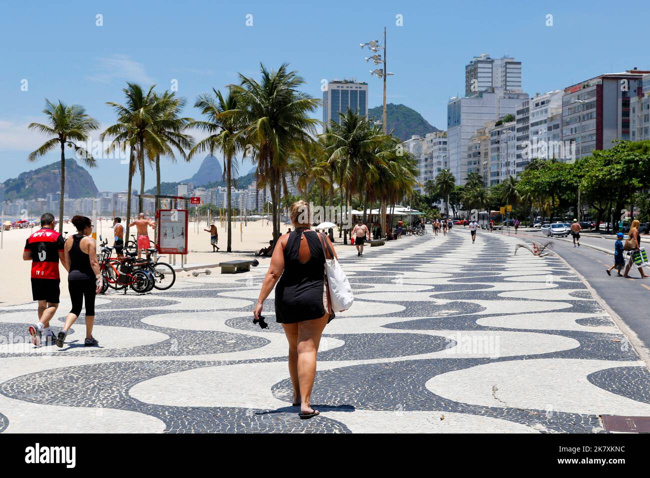 Paseo marítimo de la playa de Copacabana. Amantes de la playa caminando a la orilla del mar en la famosa acera el soleado día de fin de semana Foto de stock