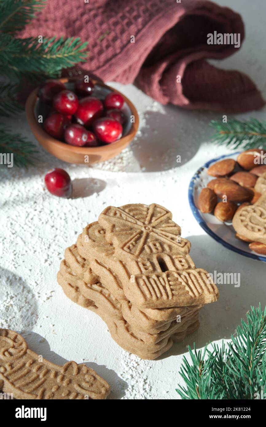Speculoos o Spekulatius, galletas de Navidad, con bayas de arándano rojo, almendras sobre una mesa con toalla de cocina y ramitas de abeto. Dulces alemanes tradicionales Foto de stock
